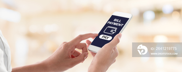 Woman hands holding and using smartphone with bill payment screen on blurred shopping mall interior 