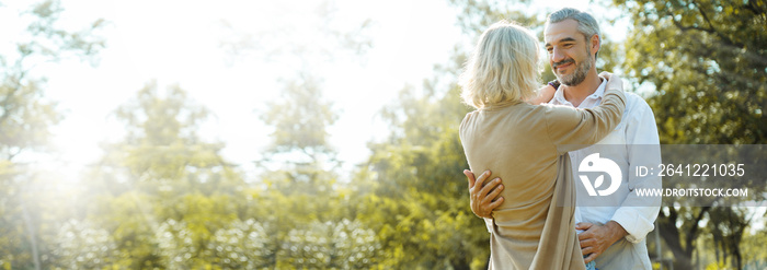 Senior Caucasian couple hugging in park. Family with a happy smile feels relaxed with nature in the 