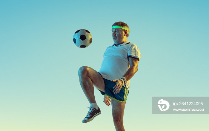 老年人踢足球，霓虹灯下渐变背景的足球。穿着gr的高加索男模