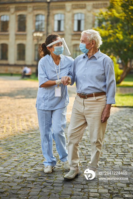 Nurse helping senior man while walking outdoors