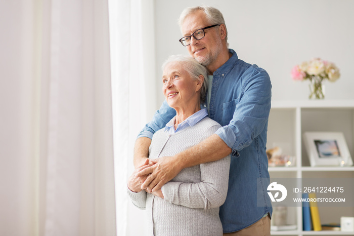 happy senior couple looking through window at home