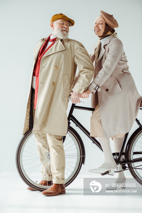 白色背景下，一对优雅的老年夫妇骑着自行车互相微笑