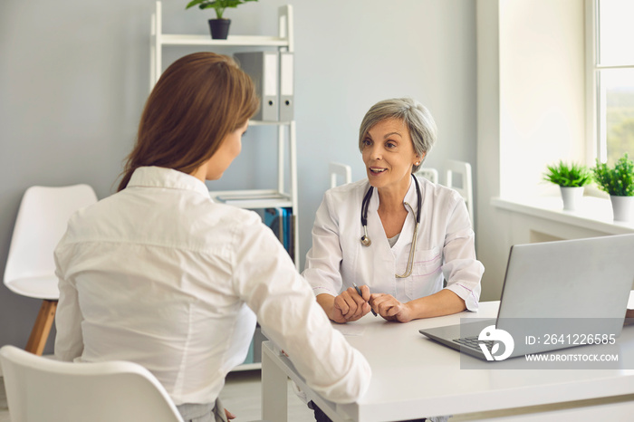 Senior woman doctor therapist consulting young woman patient in medical clinic office