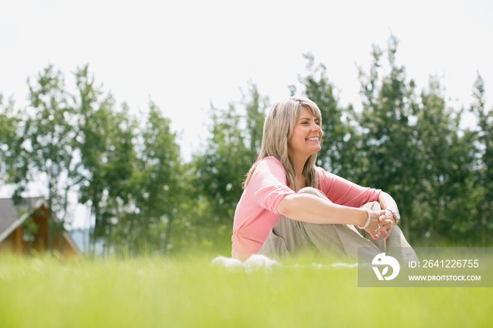 Middle aged woman sitting in grassy area