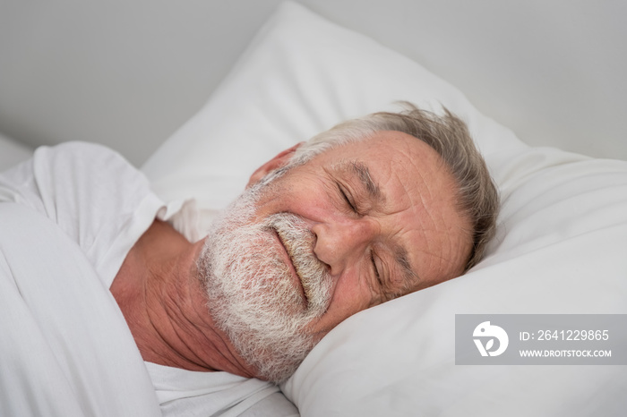 Senior elderly man sleeping happily with white blanket in bedroom