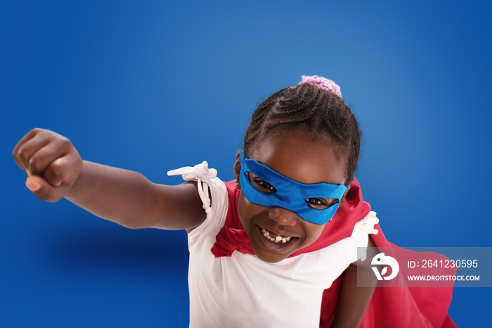 Child acts like a superhero to save the world on blue background