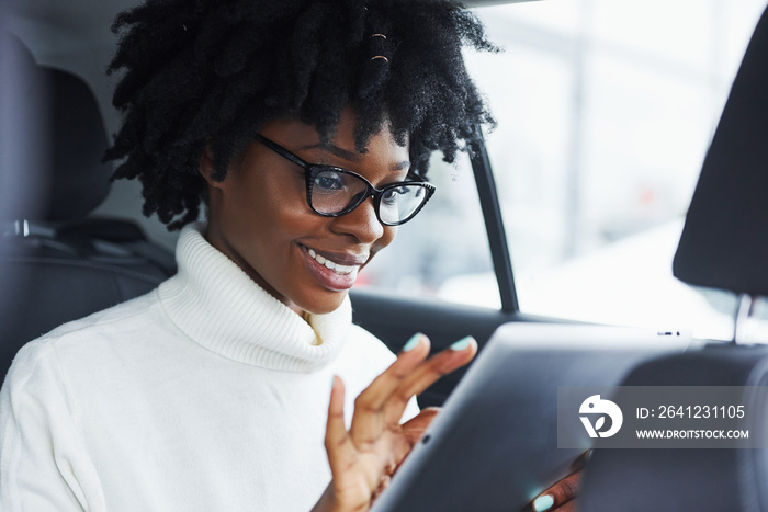 一位年轻的非裔美国女性坐在一辆新的现代汽车里，手里拿着平板电脑
