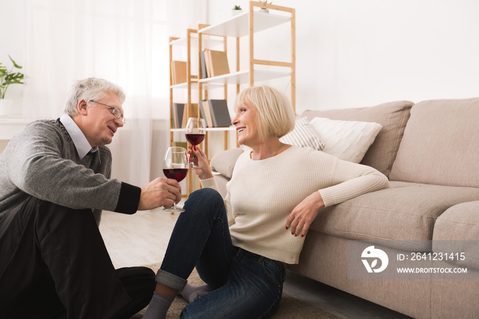 Happy senior couple drinking wine, celebrating anniversary