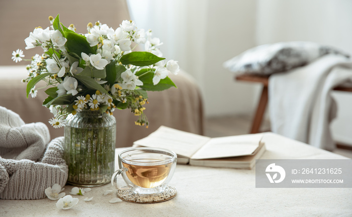 Cozy home composition with a cup of tea, a book and flowers.