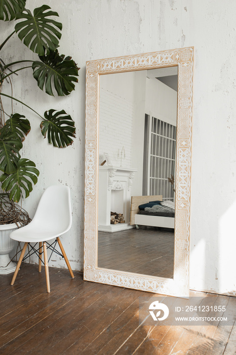 Light brown wooden mirror with ethnic pattern in a bright room with white walls.