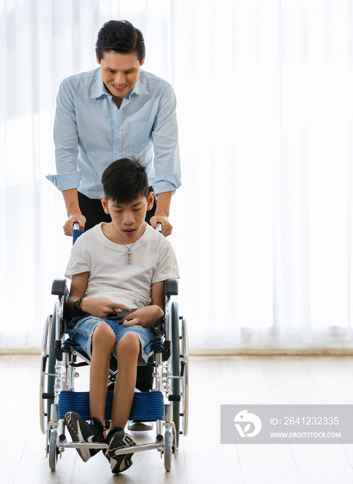 一名医生小心翼翼地推着一名残疾男孩的轮椅，做出了友善的手势