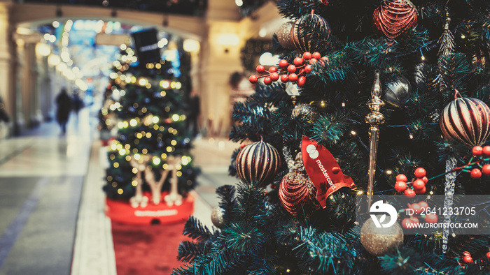 Close up of part of Christmas tree with different christmas toys and garland in shopping center. Con