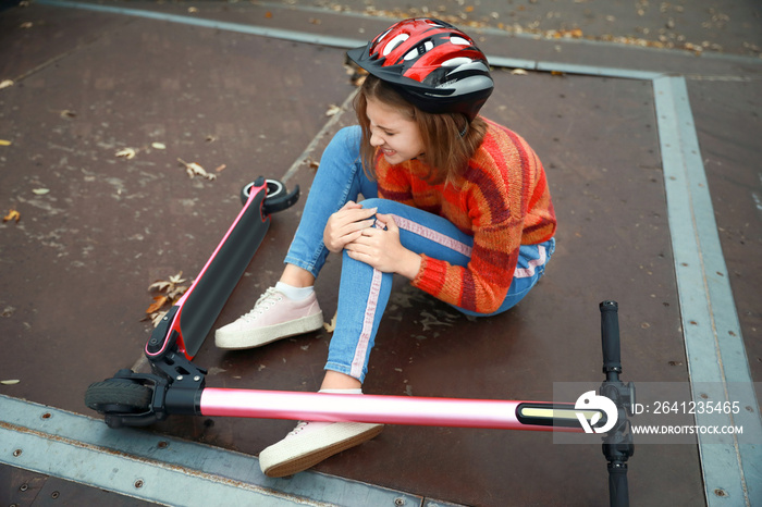 Teenage girl fallen off her kick scooter outdoors