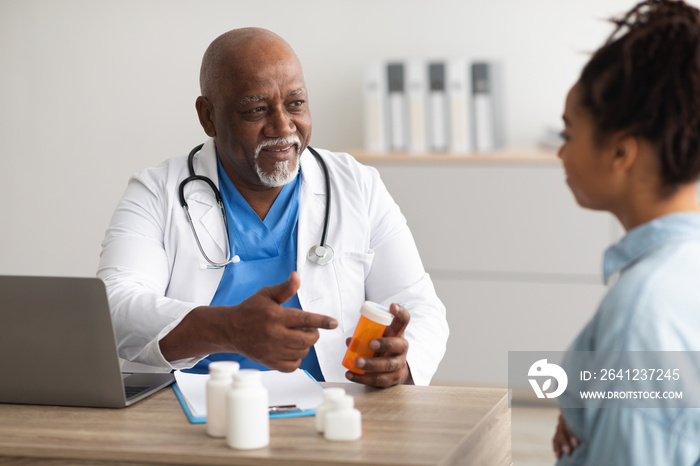 Experienced black doctor showing pills to female patient