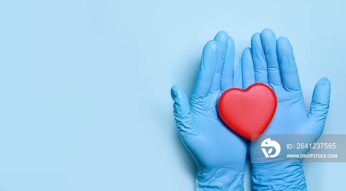 Two hands of a doctor in medical gloves hold a red heart for concept doctors treat and care for pati