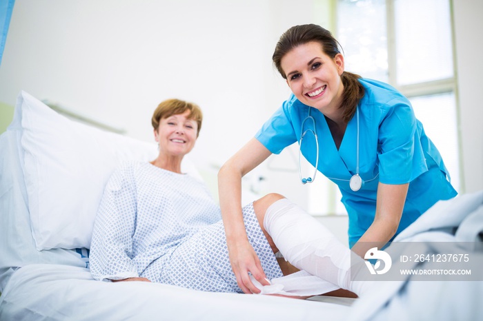 Nurse bandaging leg of patient