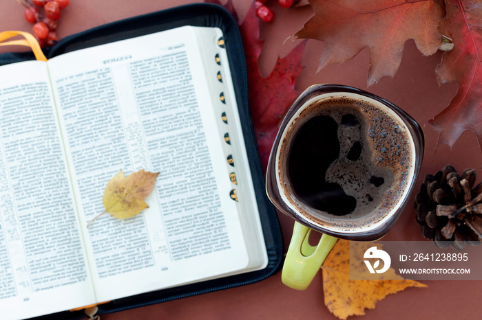 自然秋季背景下的热咖啡和书籍《圣经》。