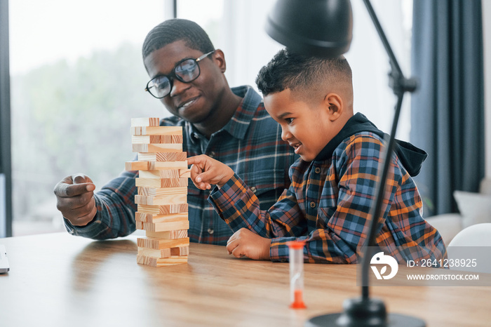 Playing bricks game. African american father with his young son at home