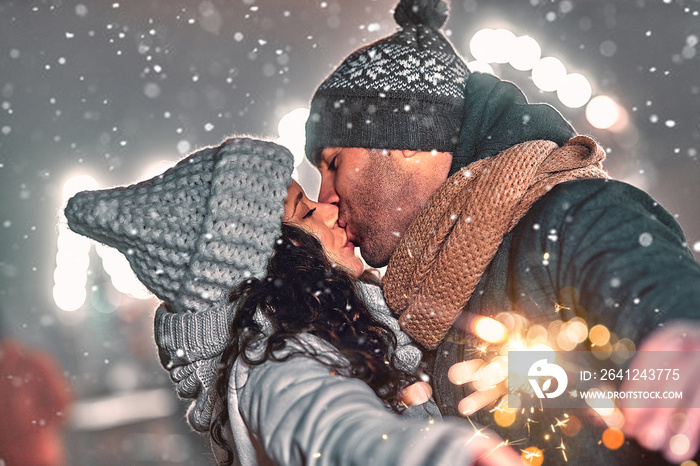 一对恩爱的情侣戴着针织帽和围巾，在t的背景下庆祝新年