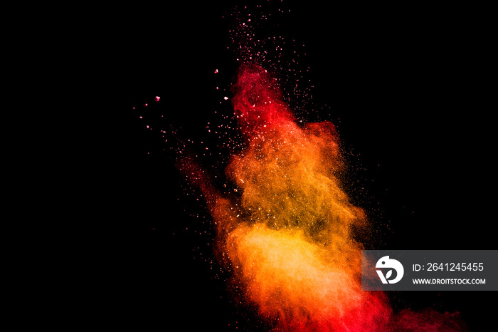 Red yellow powder explosion cloud on black background. Freeze motion of red yellow color dust partic