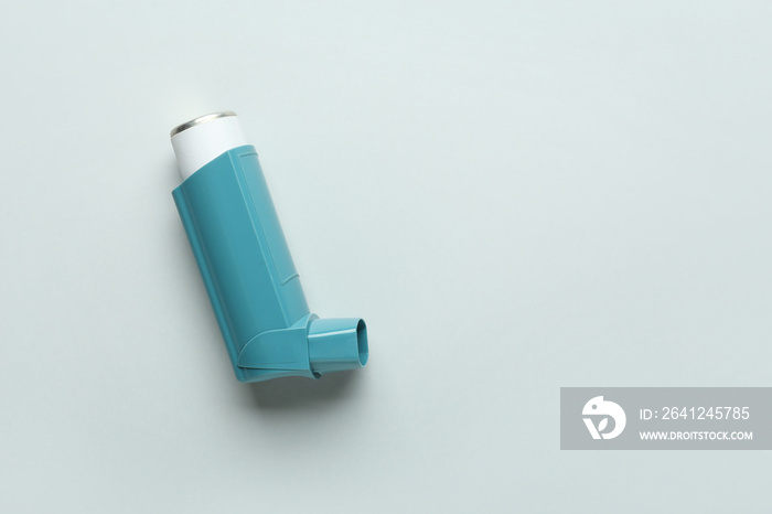 Modern asthma inhaler on grey background