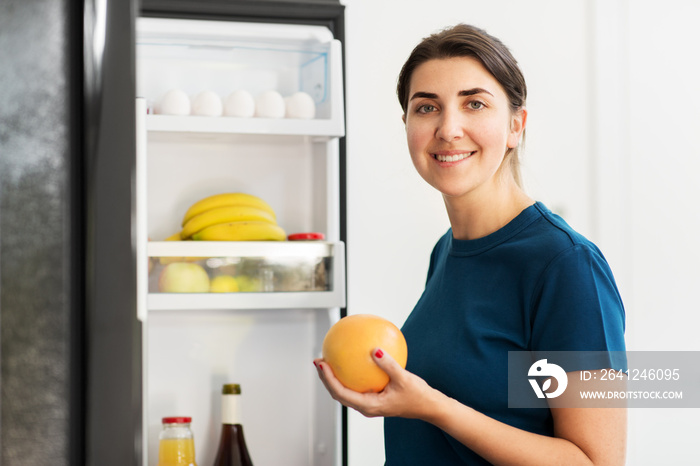健康饮食、食物和饮食理念——快乐女人在家厨房从冰箱里拿走葡萄柚