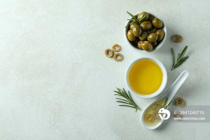 Bowls with olives and oil on white textured background