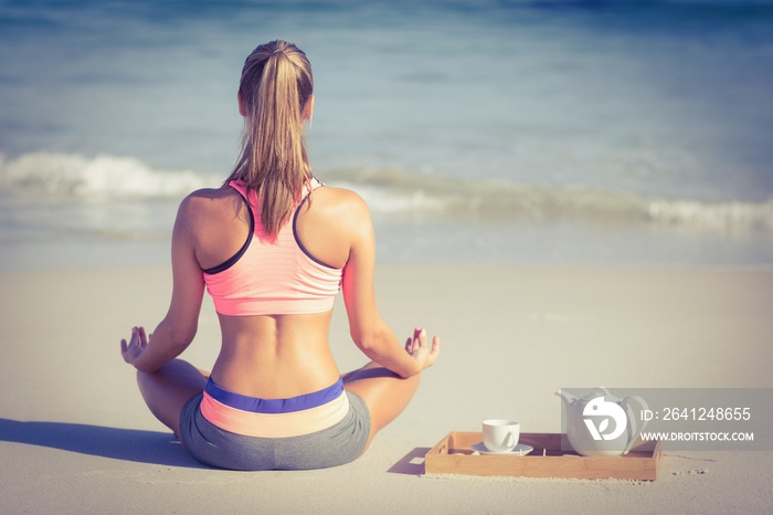 健康的女人在海滩上做瑜伽