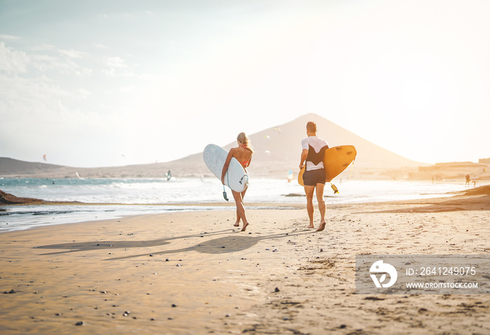 Happy surfers running with surfboards on the beach - Sporty couple having fun surfing together at su