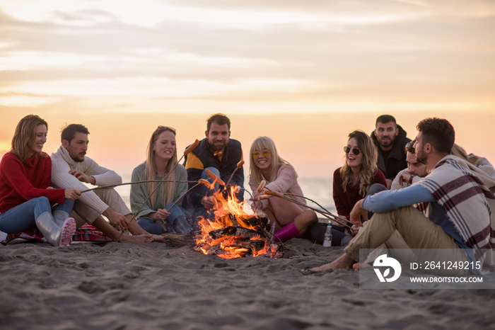 一群年轻的朋友坐在海滩的炉火旁