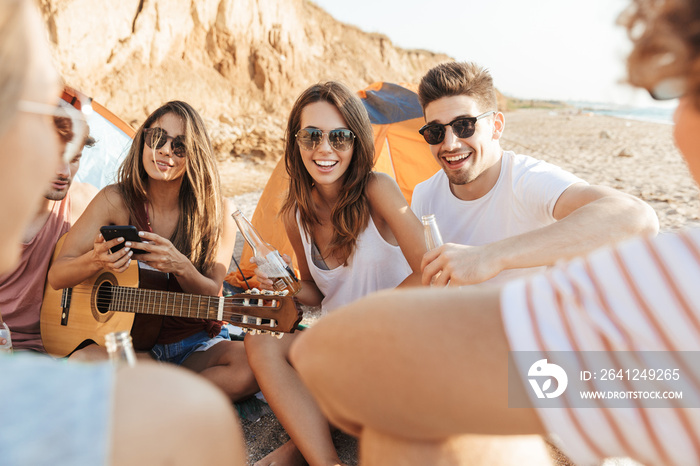 Group of cheerful happy friends camping at the beach