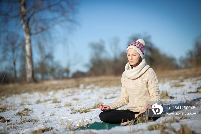 冬季或秋季，年轻的运动女性坐在雪地上冥想瑜伽姿势