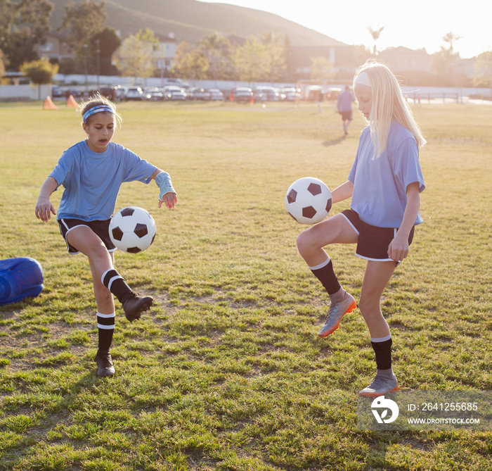 Full length of dedicated girls practicing soccer on grassy field