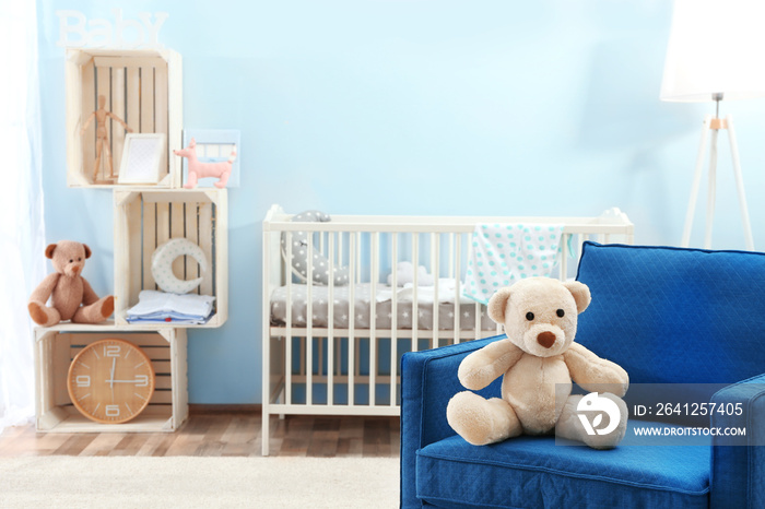 Cute teddy bear on blue armchair in baby room