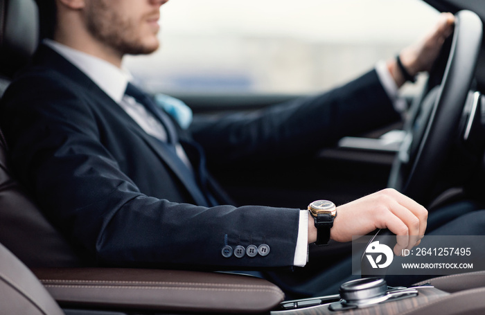 Confident man wearing suit and watch driving car