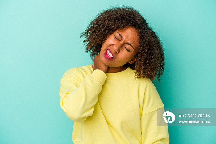 Young african american woman with curly hair isolated on blue background suffering neck pain due to 