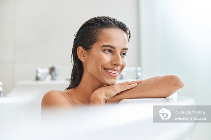 Joyful young woman taking bath at home