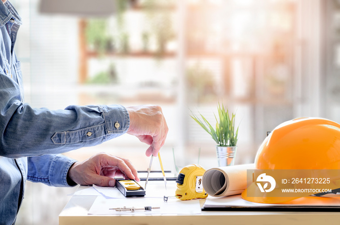 Architect hands working on blueprint with drawing tools at office.