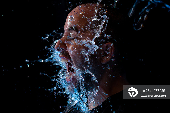 Portrait of a man being thrown water in the face against a black background