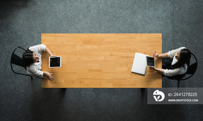 Top view two women Sit and work apart with laptop and tablet on the table social distancing concept.