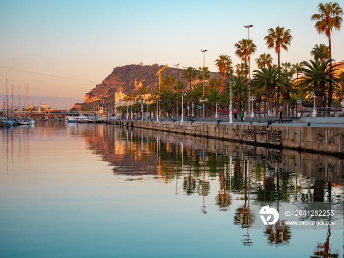 View of a promenade passing Port Vell in Barcelona during the sunrise.