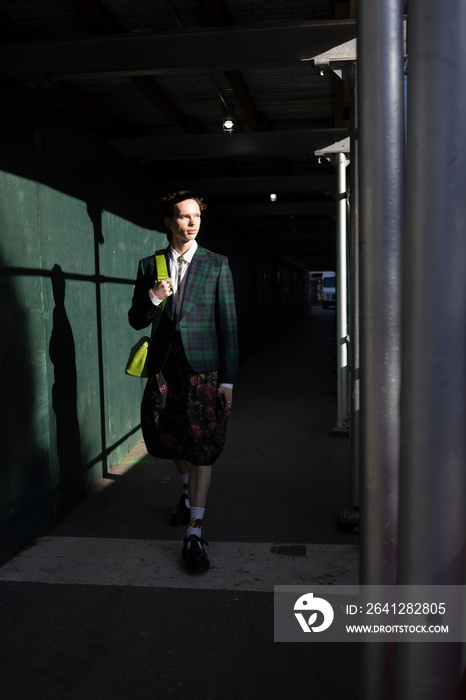 fashion portrait of non-binary person in city with dramatic sunlight