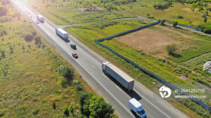 Trucks on a highway road. Transport logistic background. Aerial.