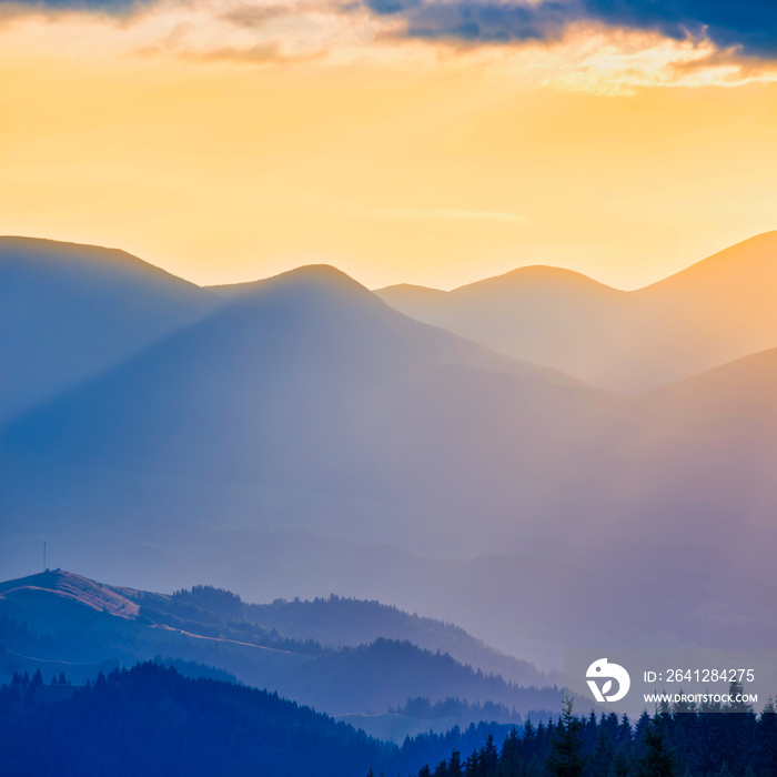 美丽的日落在山上。阳光透过橙色的云层照耀的风景