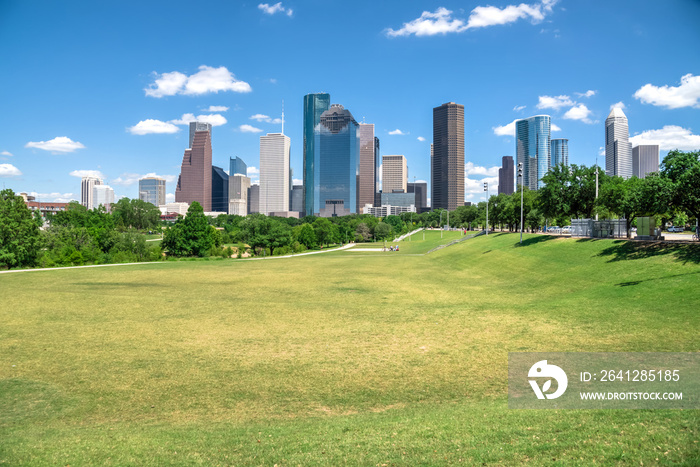 Downtown Houston at daytime with cloud blue sky. Green park lawn and modern skylines. It is the most