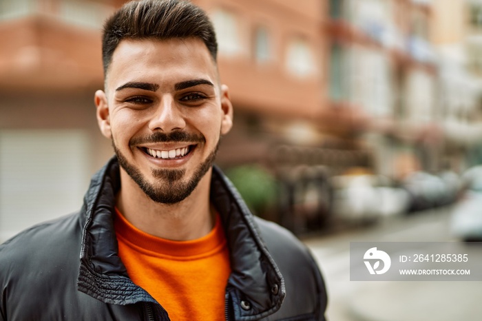 Handsome hispanic man with beard smiling happy and confident at the city wearing winter coat