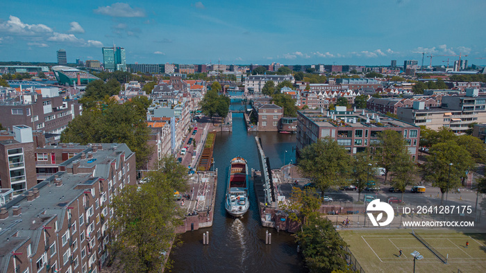 Aerial drone view of a ship passing elevating road bridge in amsterdam canal. Ship under open bridge