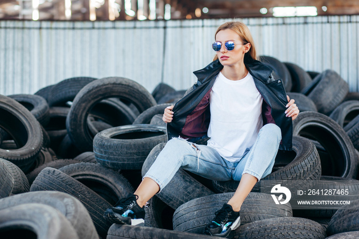 Girl wearing t-shirt, glasses and leather jacket posing against street , urban clothing style. Stree