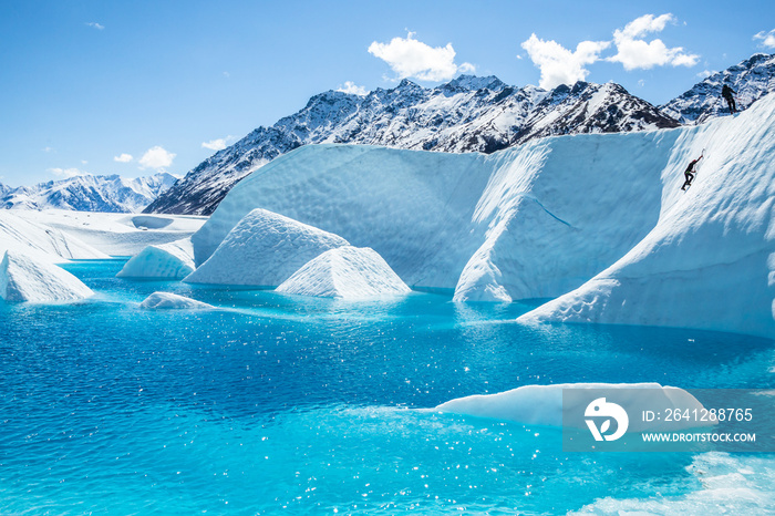 攀登者在马塔努斯卡冰川上的一个蓝色冰川湖上爬上一堵巨大的冰墙。