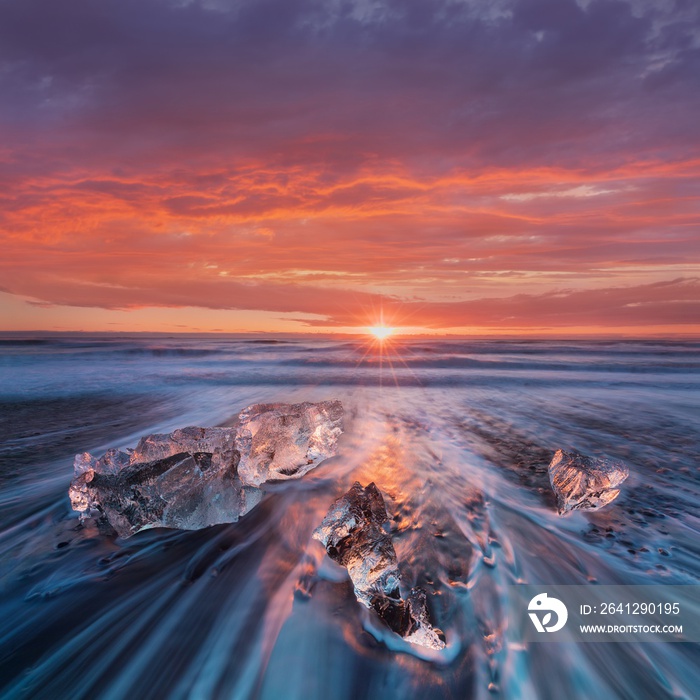 Beautiful sunset over famous Diamond beach, Iceland. This sand lava beach is full of many giant ice 